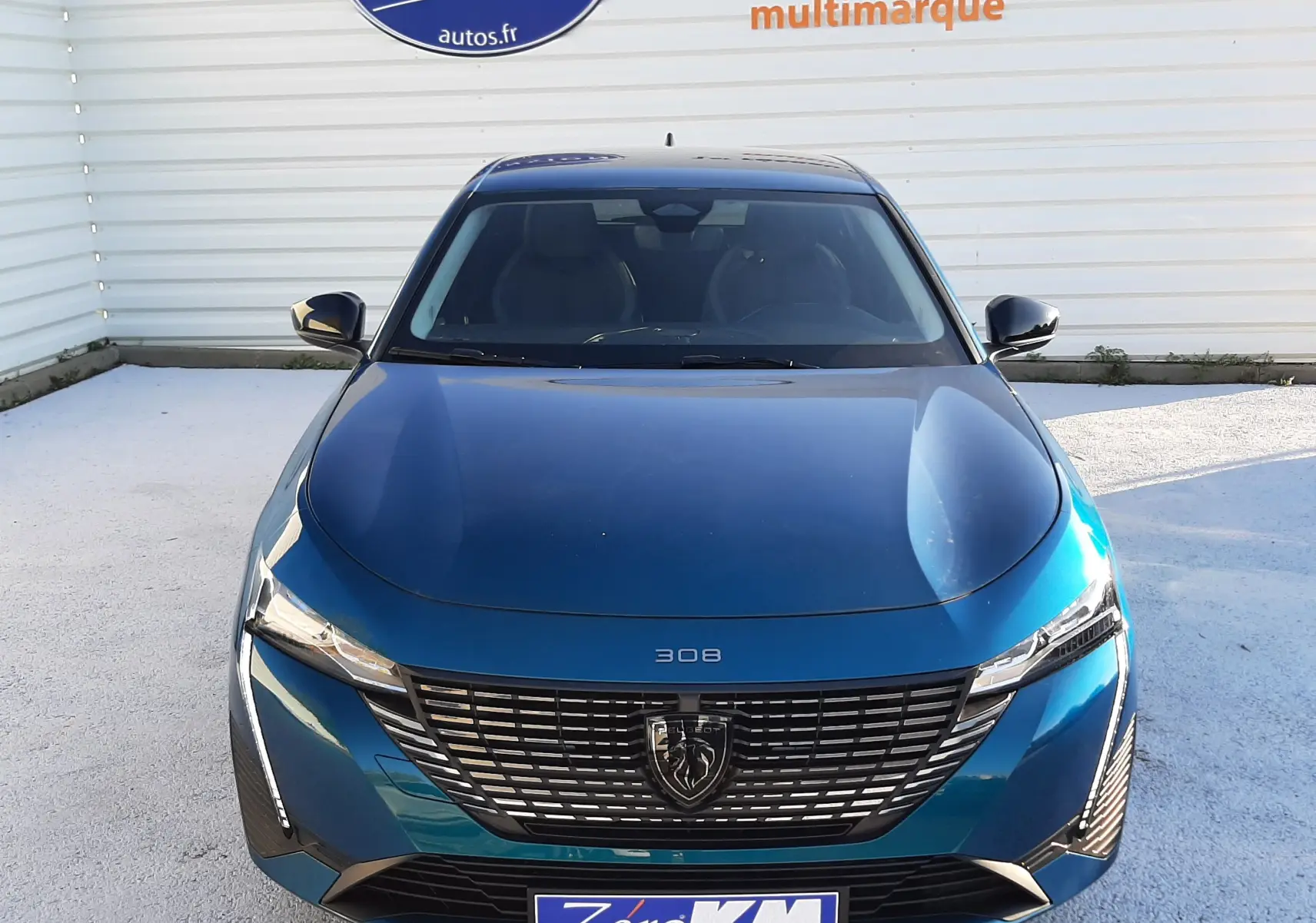 Vue frontale d'une Peugeot 308 Bleu Obsession 2025 avec calandre noire et logo lion distinctif.