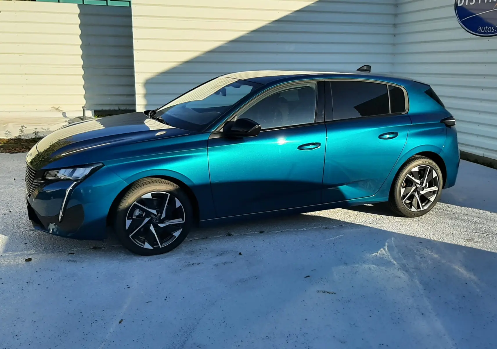 Peugeot 308 Bleu Obsession vue de profil côté gauche, avec jantes noires et design moderne sous un ciel dégagé.