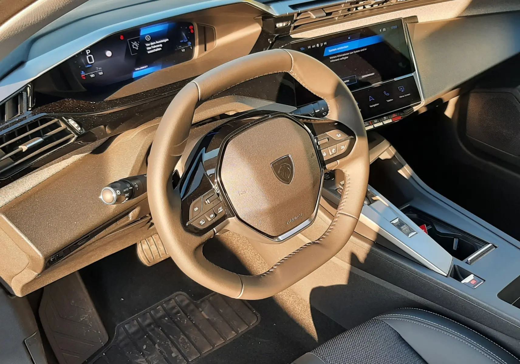 Intérieur Peugeot 308 2025 vue du poste de conduite, volant compact et tableau de bord numérique moderne noir.