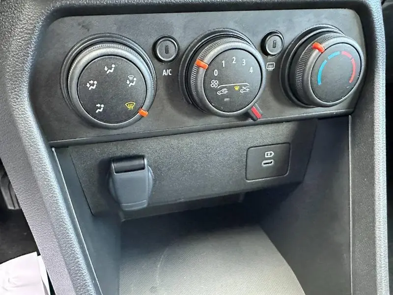 Gros plan sur les commandes de climatisation manuelle et prises USB d'une Dacia Sandero blanche 2025, version Stepway Expression.