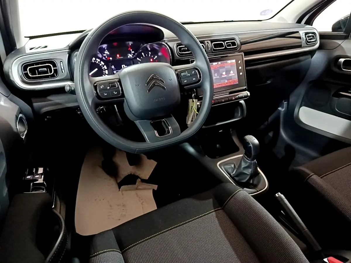 Vue intérieure avant de la Citroën C3 PureTech blanche 2023, tableau de bord avec écran tactile et volant multifonctions.