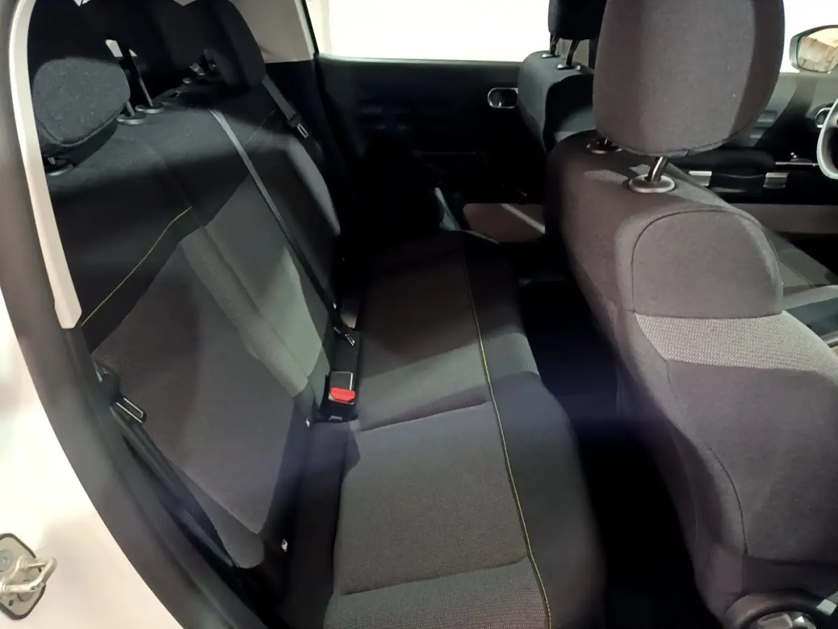 Vue intérieure côté gauche montrant la banquette arrière noire avec surpiqûres jaunes d'une Citroën C3 blanche 2023.