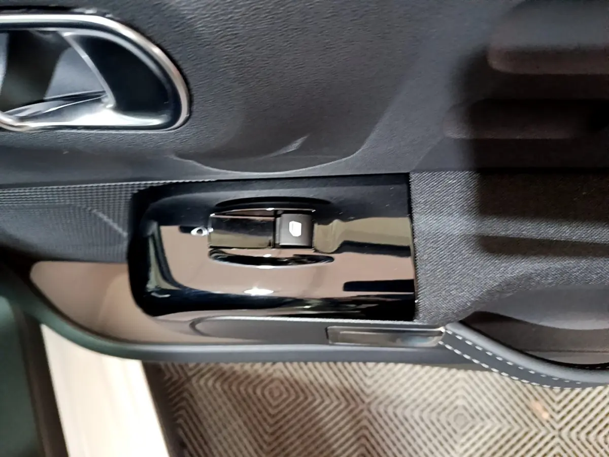 Commande de lève-vitre électrique côté gauche sur la porte intérieure noire d'une Citroën C3 blanche 2023.