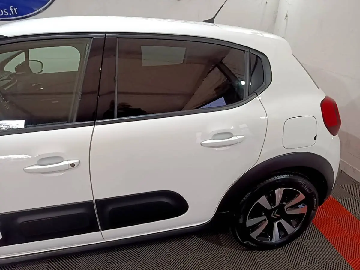 Vue latérale droite sur la partie arrière d'une Citroën C3 blanche avec protections noires et jantes stylisées.