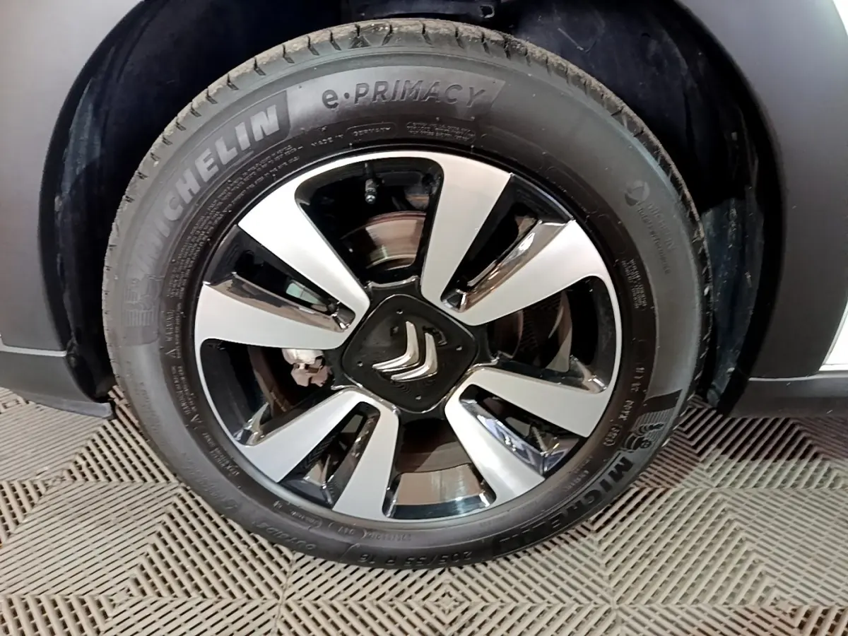 Gros plan sur la jante alliage bicolore avec logo Citroën au centre d'une roue Michelin d'une Citroën C3 blanche.