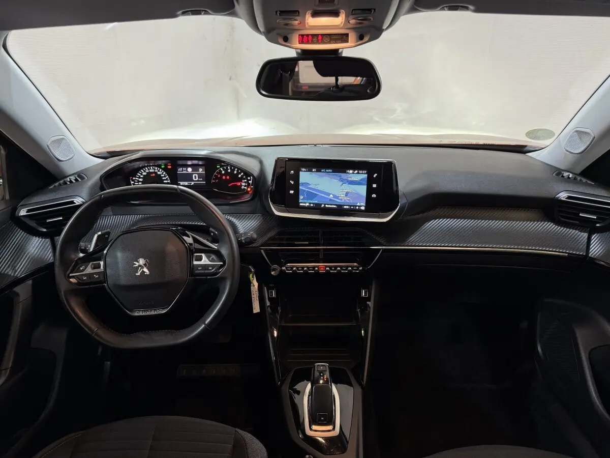 Vue intérieure frontale du tableau de bord noir de la Peugeot 2008 avec écran tactile central et volant multifonctions.