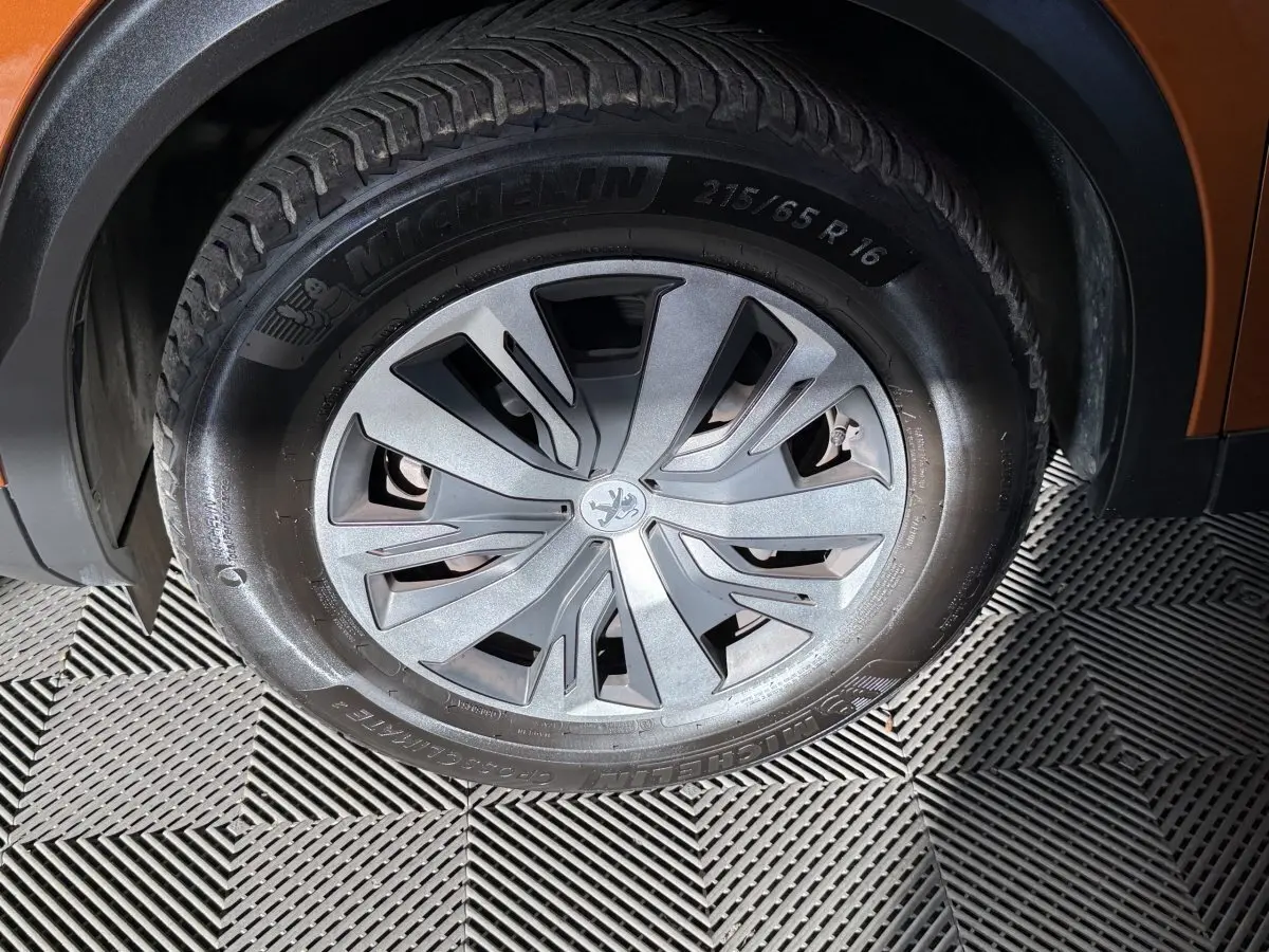 Gros plan sur la roue avant droite du Peugeot 2008 orange, mettant en valeur la jante et le pneu Michelin.