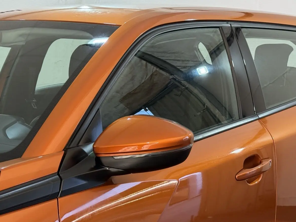 Gros plan sur le rétroviseur droit orange et la porte avant droite d’un Peugeot 2008 2022 en intérieur.