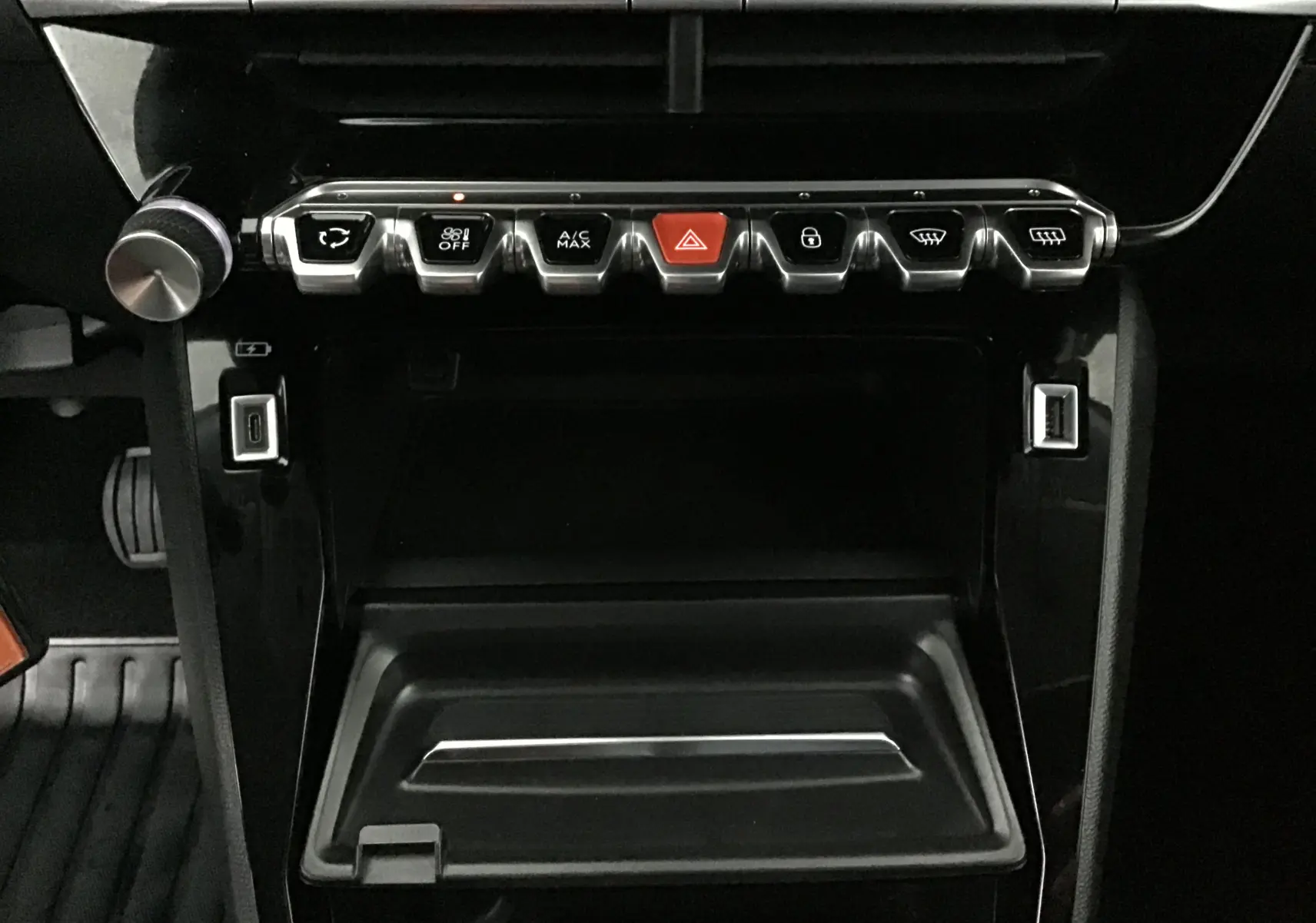 Gros plan sur la console centrale noire du Peugeot 2008 1.2 PureTech 100 Allure, avec boutons de commande et ports USB visibles.