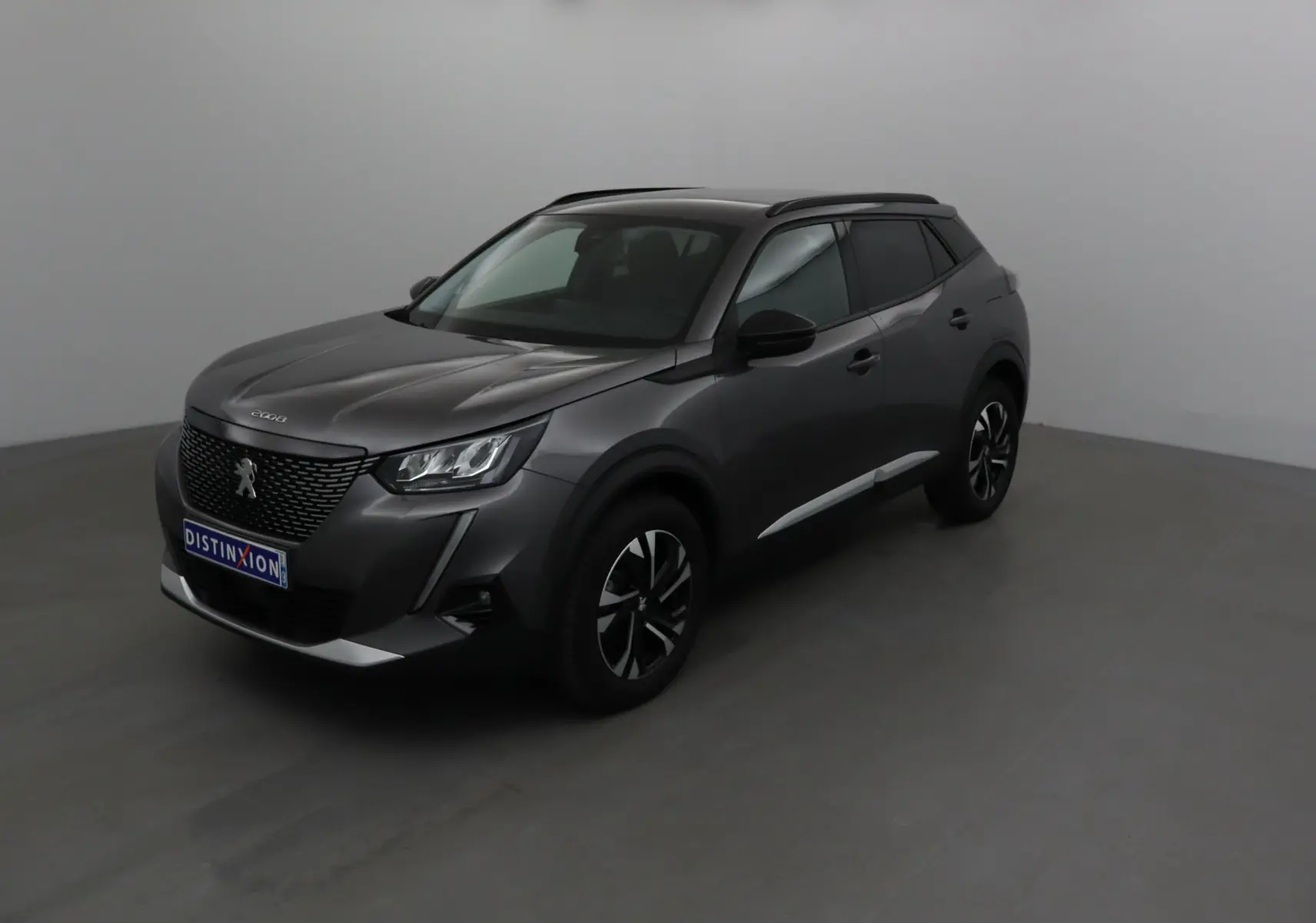 Peugeot 2008 gris platinium en 3/4 avant droit, avec calandre noire et jantes alliage bicolores.