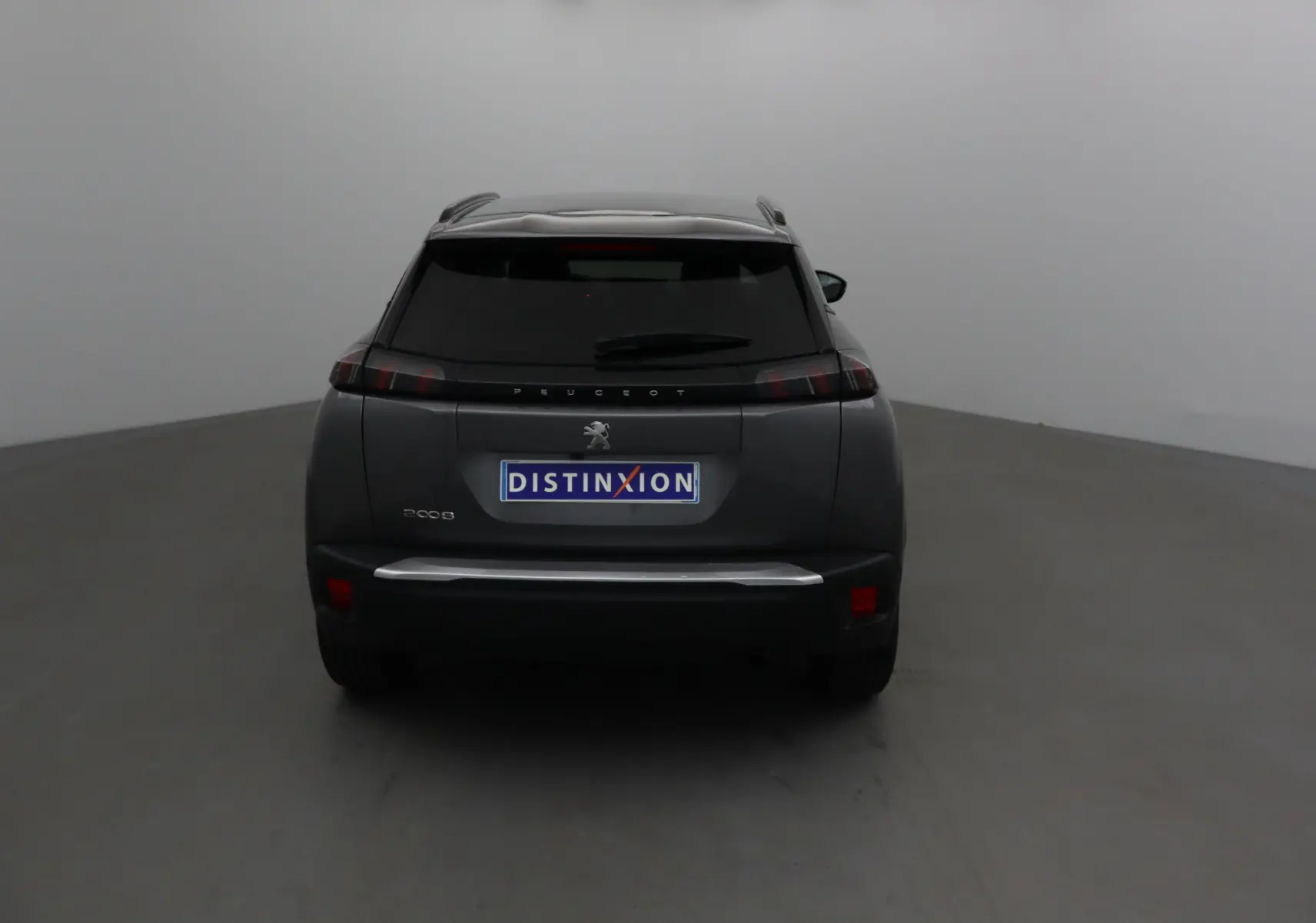 Vue arrière d'un Peugeot 2008 gris platinium 2022 avec feux arrière noirs et logo distinctif au centre.