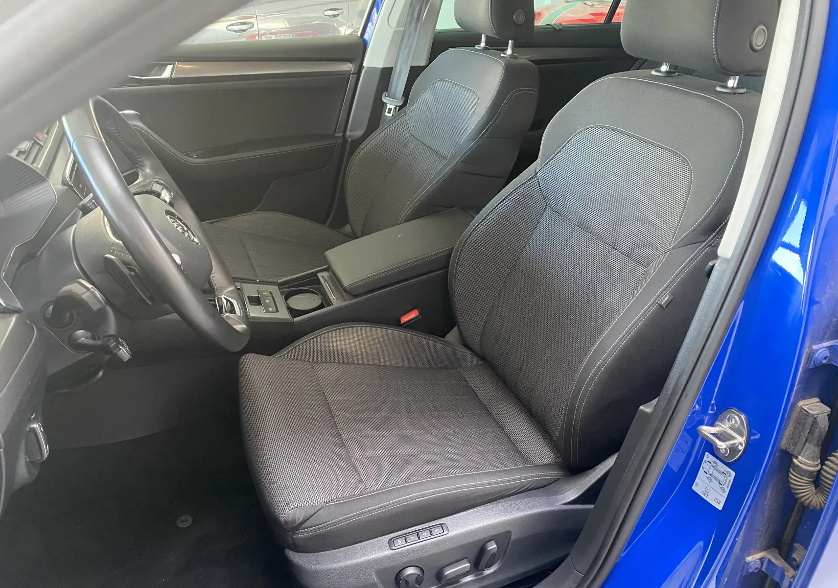 Intérieur avant droit de la Skoda Superb Combi bleu énergie 2020, sièges tissu gris et commandes électriques visibles.