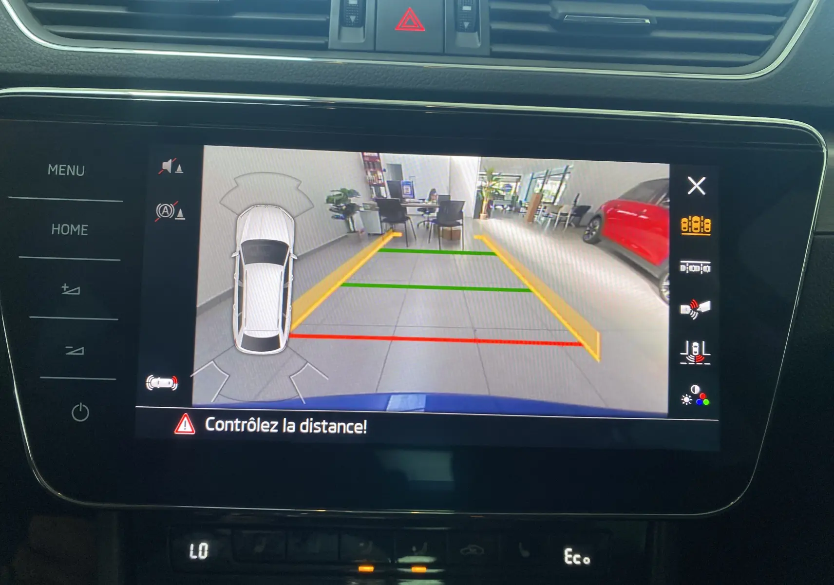 Vue de l'écran multimédia d'une Skoda Superb Combi bleu énergie montrant la caméra de recul avec guidage de trajectoire.