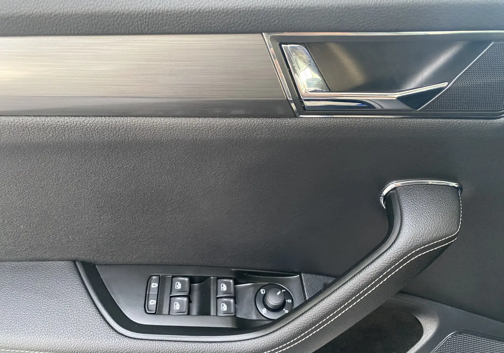 Intérieur de la porte avant gauche d'une Skoda Superb Combi 2020, avec garniture noire et poignée cuir surpiquée.