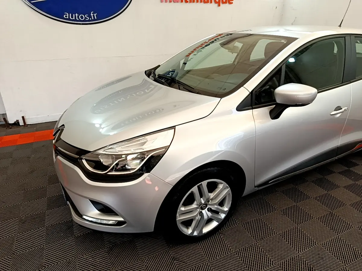 Vue 3/4 avant droit d'une Renault Clio Business TCe 90 gris clair avec phares LED et jantes alliage visibles.