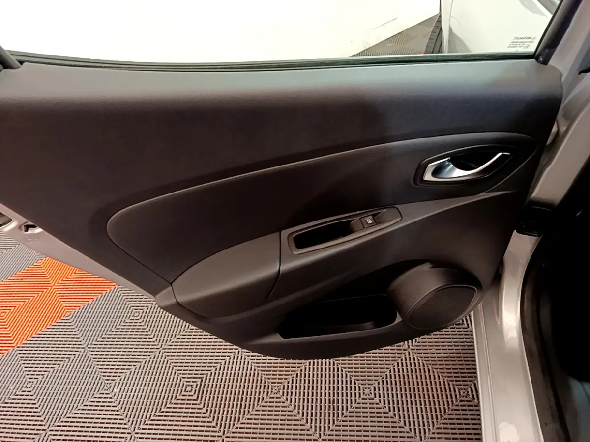 Vue rapprochée de la porte arrière droite gris clair d'une Renault Clio 2019 avec poignée et commande de vitre noire.