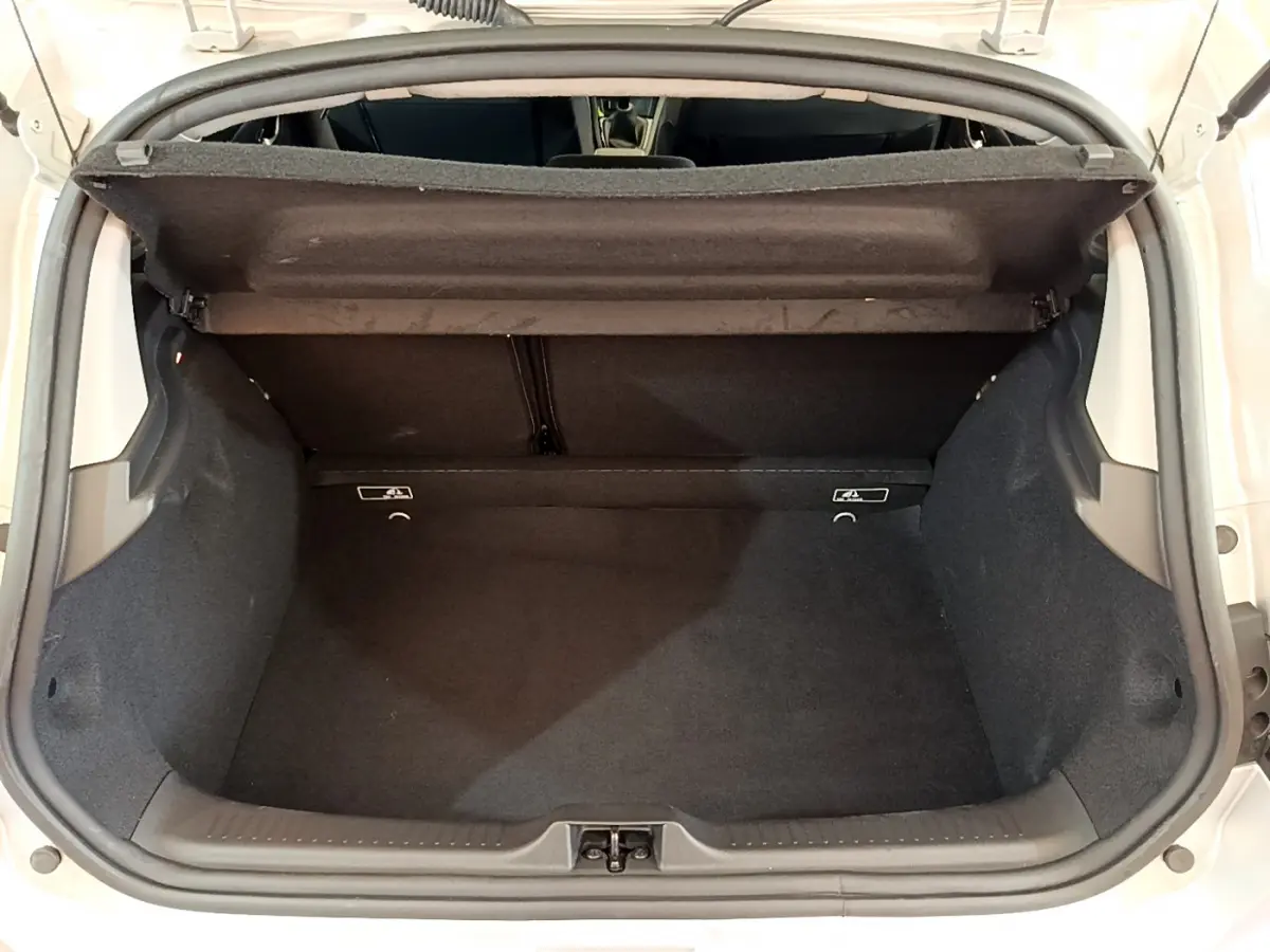 Coffre ouvert d'une Renault Clio gris clair, vue de dessus montrant l'espace de chargement vide et la tablette arrière.