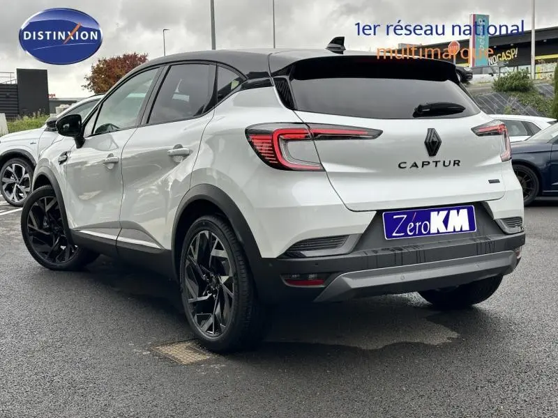 Vue 3/4 arrière droite d'un Renault Captur 2025 blanc avec toit noir et jantes noires esprit Alpine.