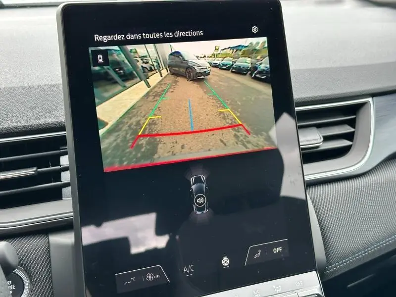 Écran intérieur montrant la caméra de recul avec vue arrière d'un Renault Captur 1.6 E-Tech hybride gris en stationnement.