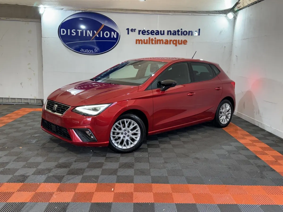 SEAT Ibiza 1.0 TSI 110 FR rouge vue 3/4 avant droit dans un showroom avec sol noir et orange.
