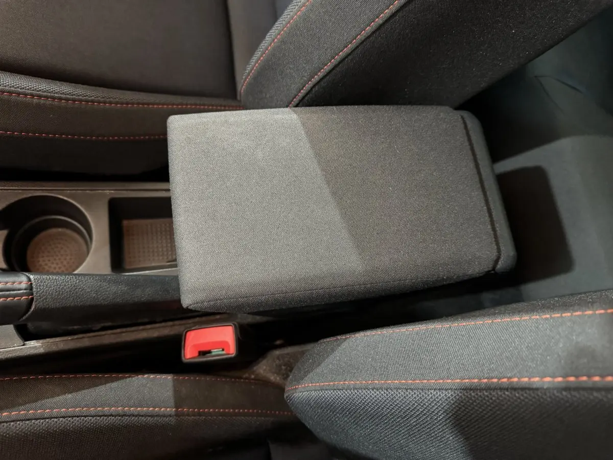 Gros plan sur l'accoudoir central et la console noire avec surpiqûres rouges dans l'habitacle d'une SEAT Ibiza 2024.