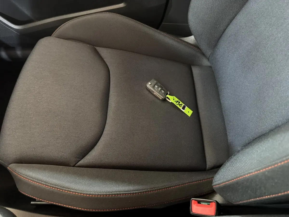 Gros plan sur le siège avant droit noir avec surpiqûres rouges et clé de contact SEAT Ibiza 2024 posée dessus.