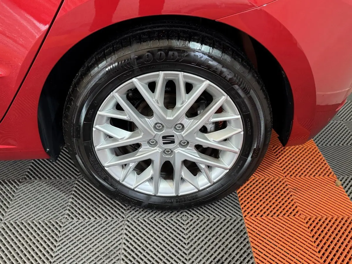 Gros plan sur la roue avant droite argentée d'une SEAT Ibiza rouge 2024, soulignant la jante en alliage et le pneu Goodyear.