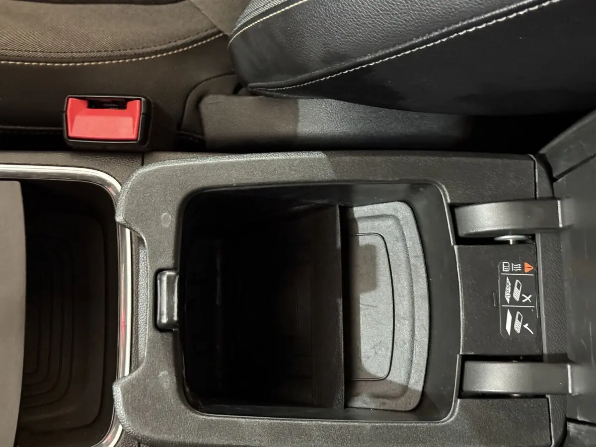 Vue plongeante sur le rangement central ouvert de l’Opel Grandland X noir, avec siège en cuir et ceinture rouge visible.