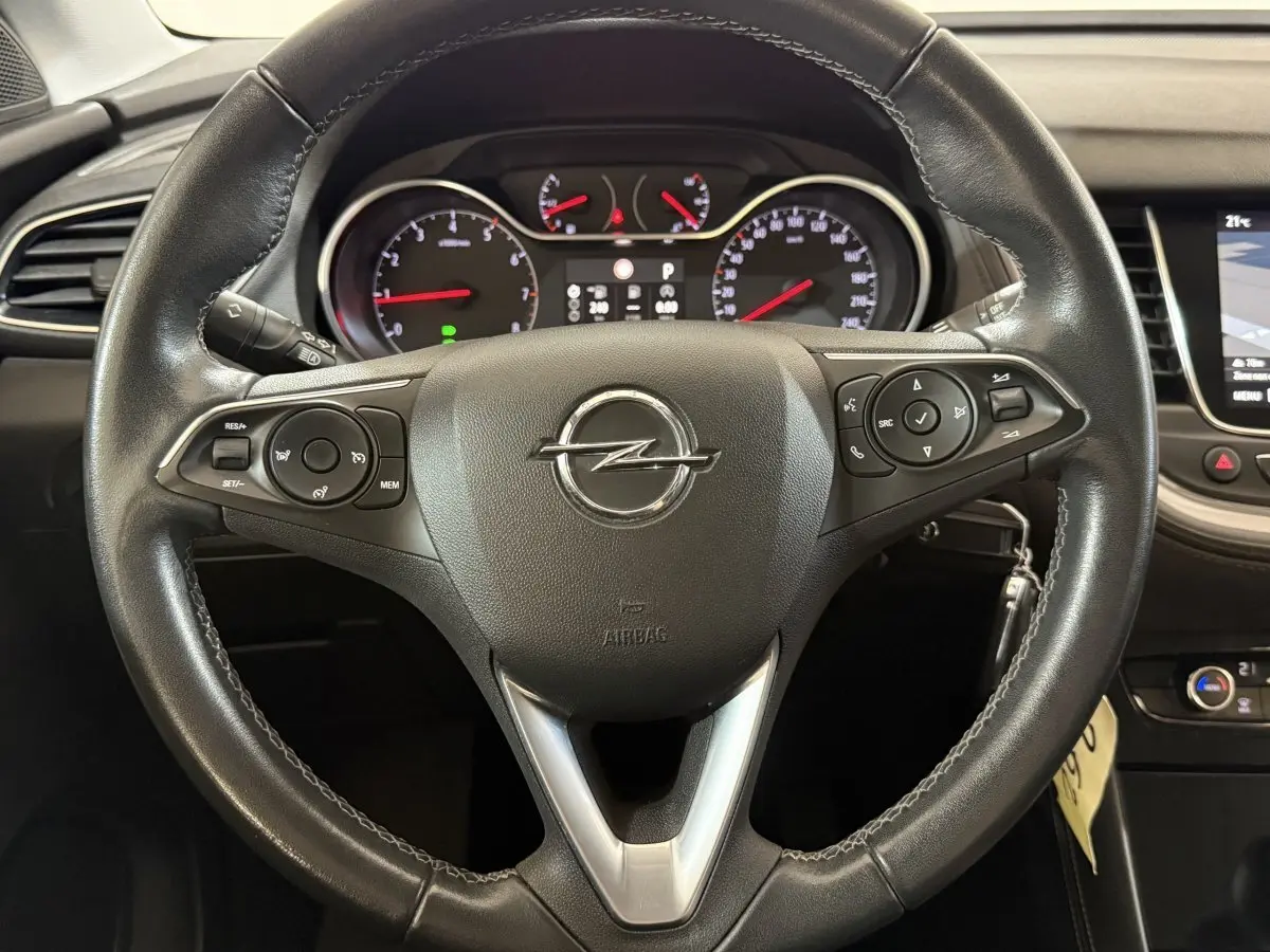 Vue rapprochée du volant en cuir noir de l'Opel Grandland X avec commandes intégrées et tableau de bord digital.