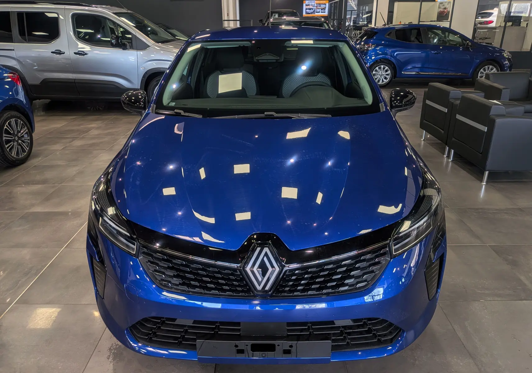 Vue avant d'une Renault Clio V Bleu Iron 2025, mettant en valeur sa calandre noire et ses phares LED fins.