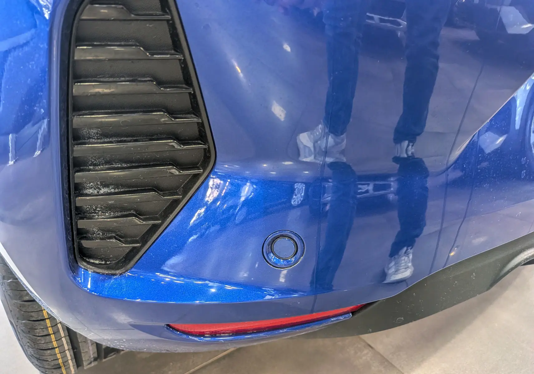 Détail du pare-chocs arrière bleu Iron de la Renault Clio V avec capteur de recul et diffuseur noir.