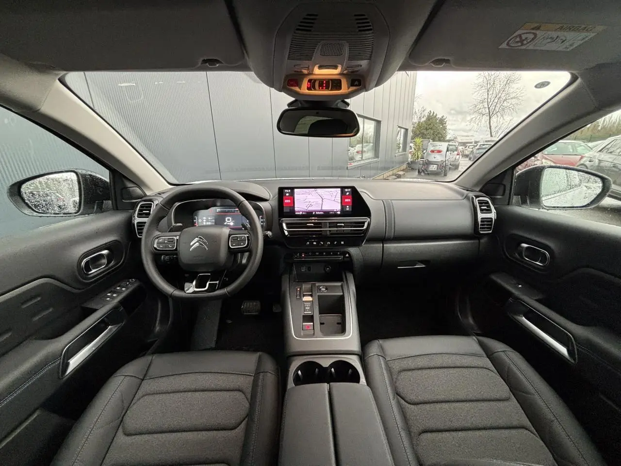 Vue intérieure avant du Citroën C5 Aircross 2025, tableau de bord noir avec écran tactile et volant multifonction.