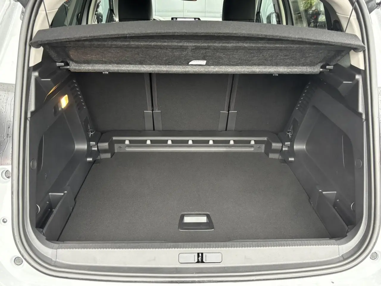 Coffre ouvert vu de l'arrière du Citroën C5 Aircross blanc Okénite, montrant un espace de chargement propre et modulable.
