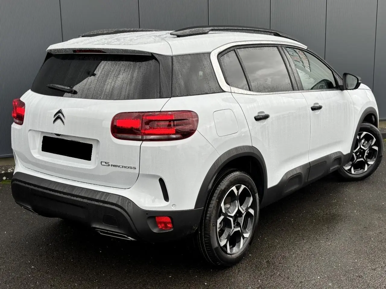 Vue 3/4 arrière droite d’un Citroën C5 Aircross blanc Okénite avec jantes alliage bi-ton et vitres surteintées.