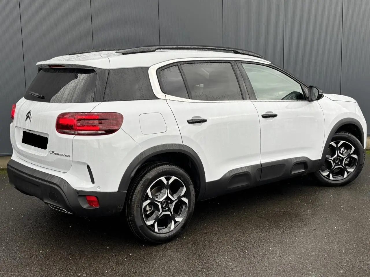 Vue 3/4 arrière droite d'un Citroën C5 Aircross blanc Okénite avec jantes alliage bi-ton et vitres surteintées.