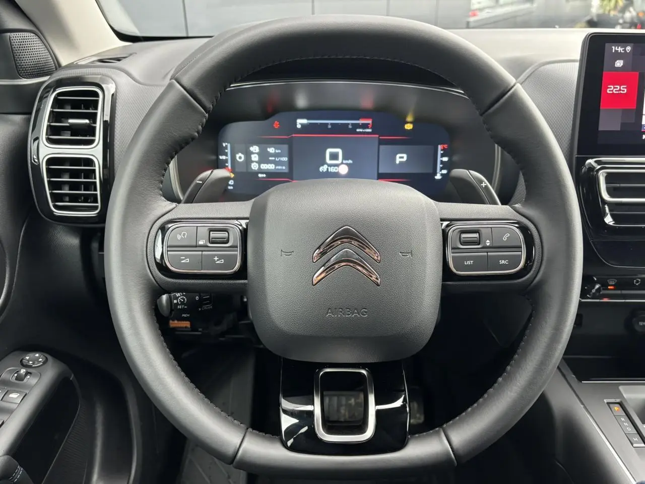 Vue intérieure centrée sur le volant noir cuir du Citroën C5 Aircross 2025 avec tableau de bord numérique et écran tactile.