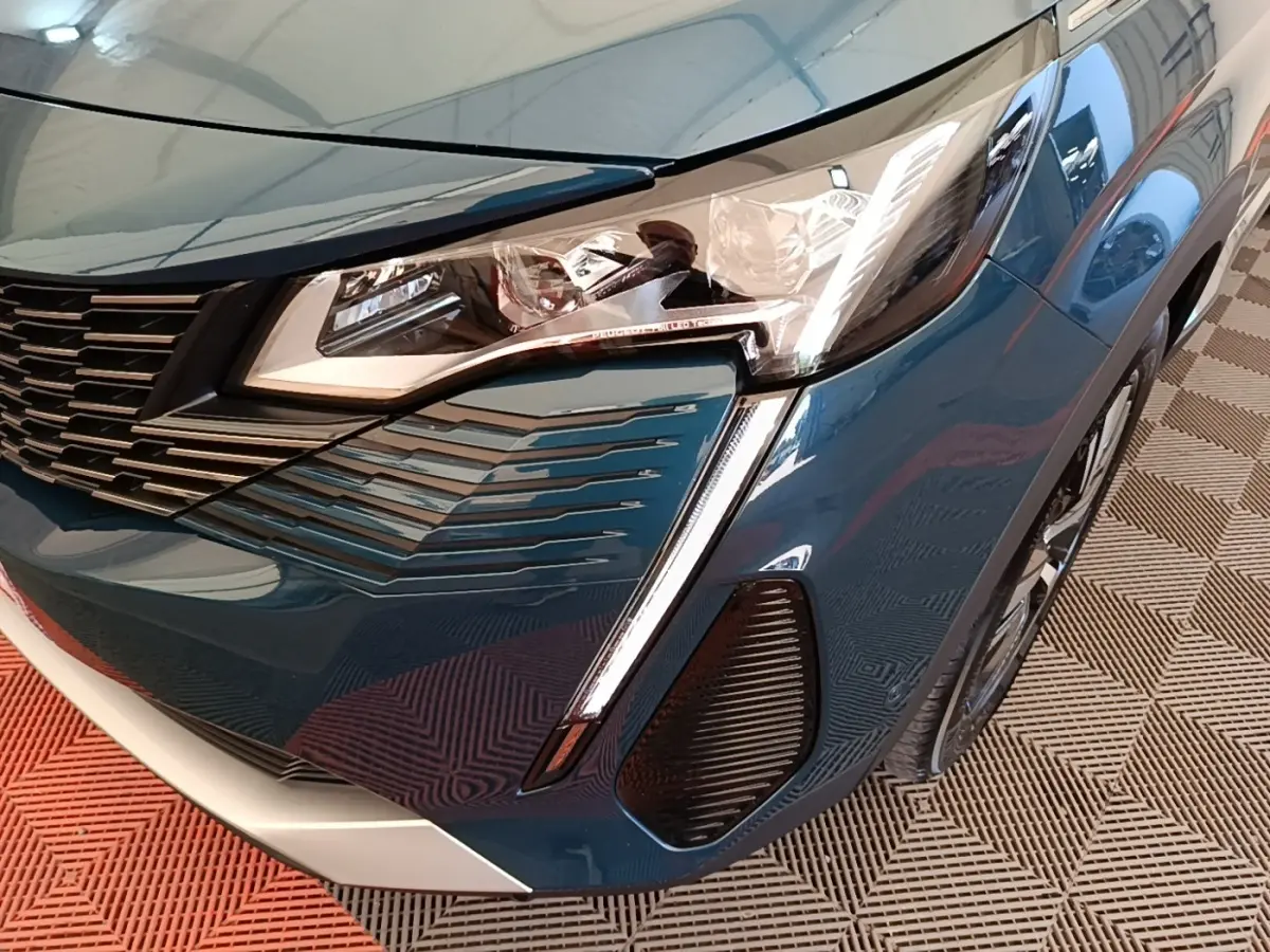 Gros plan sur l’avant droit bleu du Peugeot 3008 1.6 Hybrid 225 GT avec phares LED et calandre distinctive.