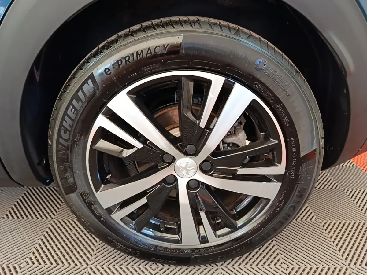 Gros plan sur la jante alliage bicolore et pneu Michelin e-Primacy du Peugeot 3008 bleu hybride rechargeable.