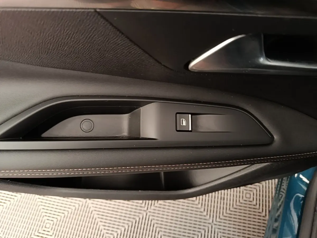 Détail de la commande de lève-vitre côté gauche sur porte intérieure noire du Peugeot 3008 bleu 2022 hybride rechargeable.