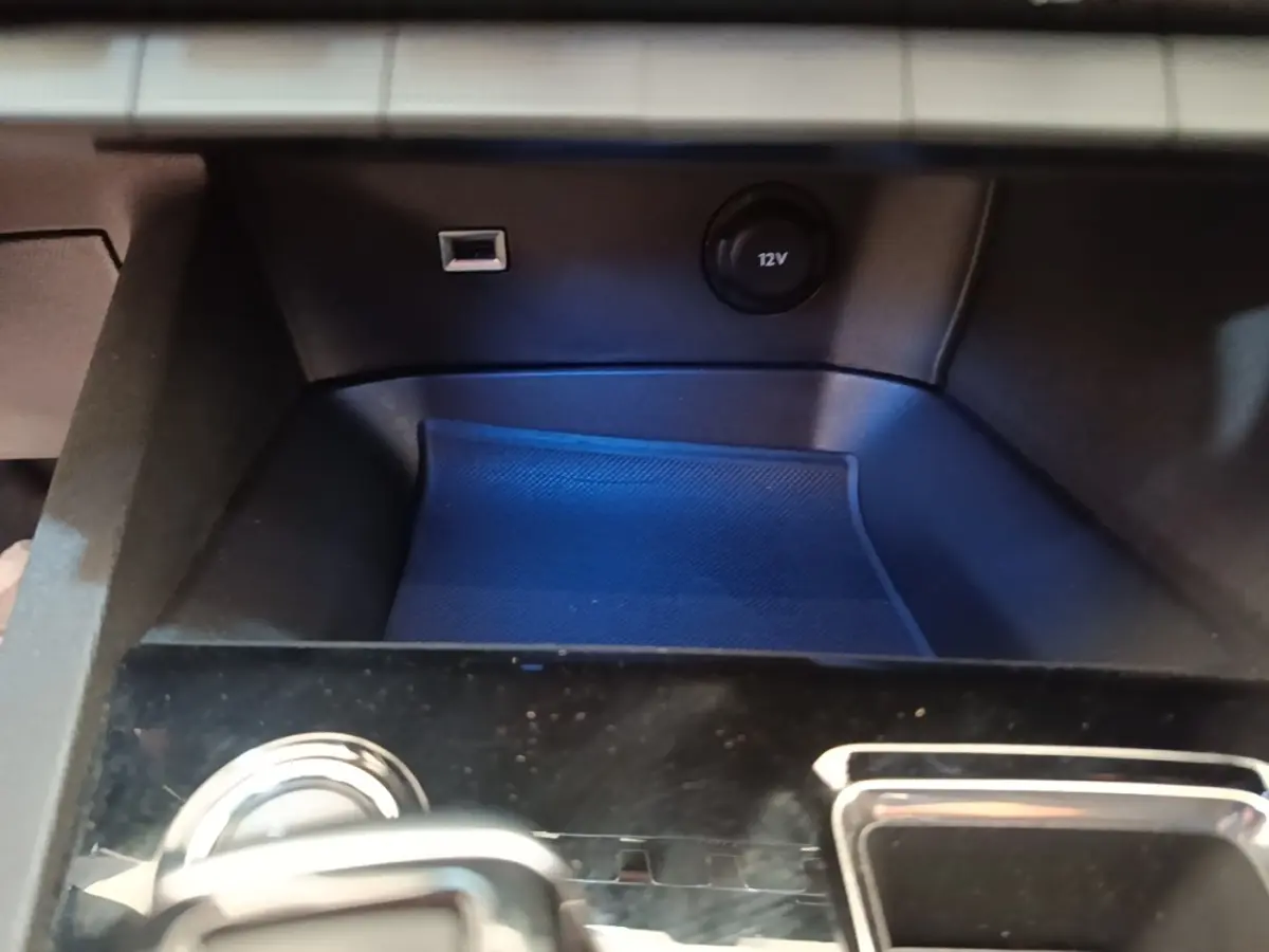 Gros plan sur la console centrale noire du Peugeot 3008 hybride, avec prise USB et prise 12V visibles.