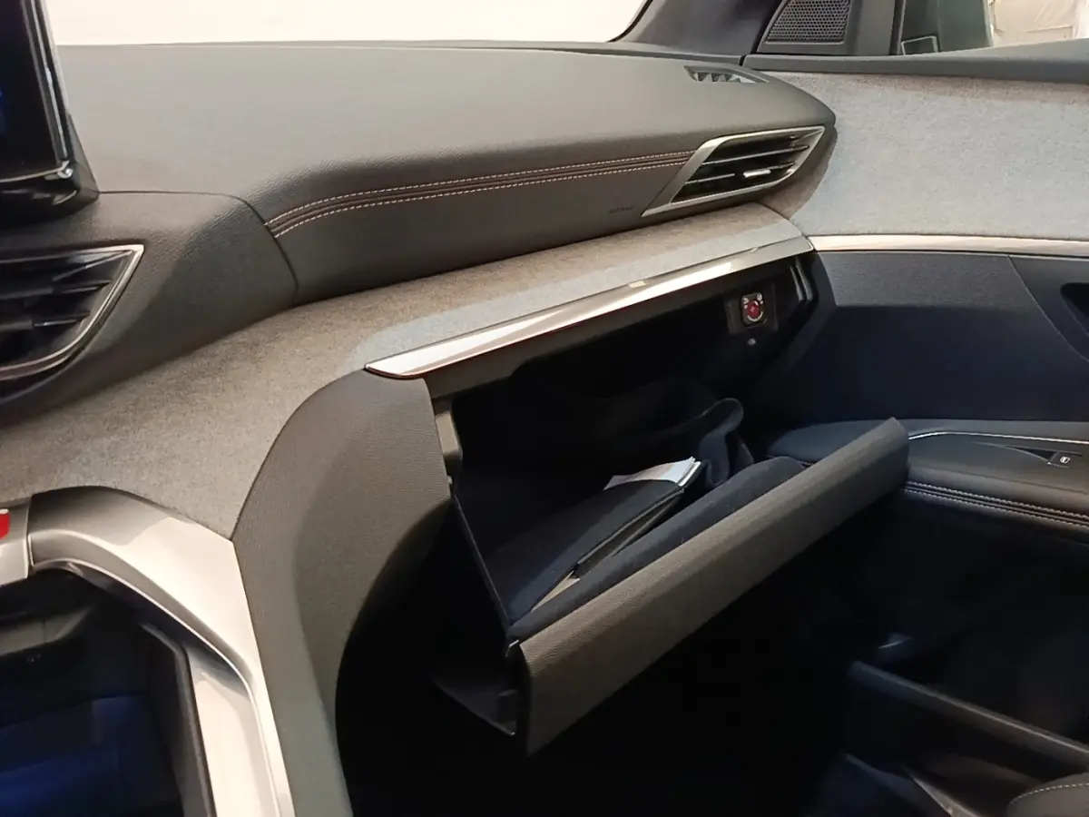 Intérieur côté passager du Peugeot 3008 Hybrid 2022, tableau de bord gris et noir avec boîte à gants ouverte.