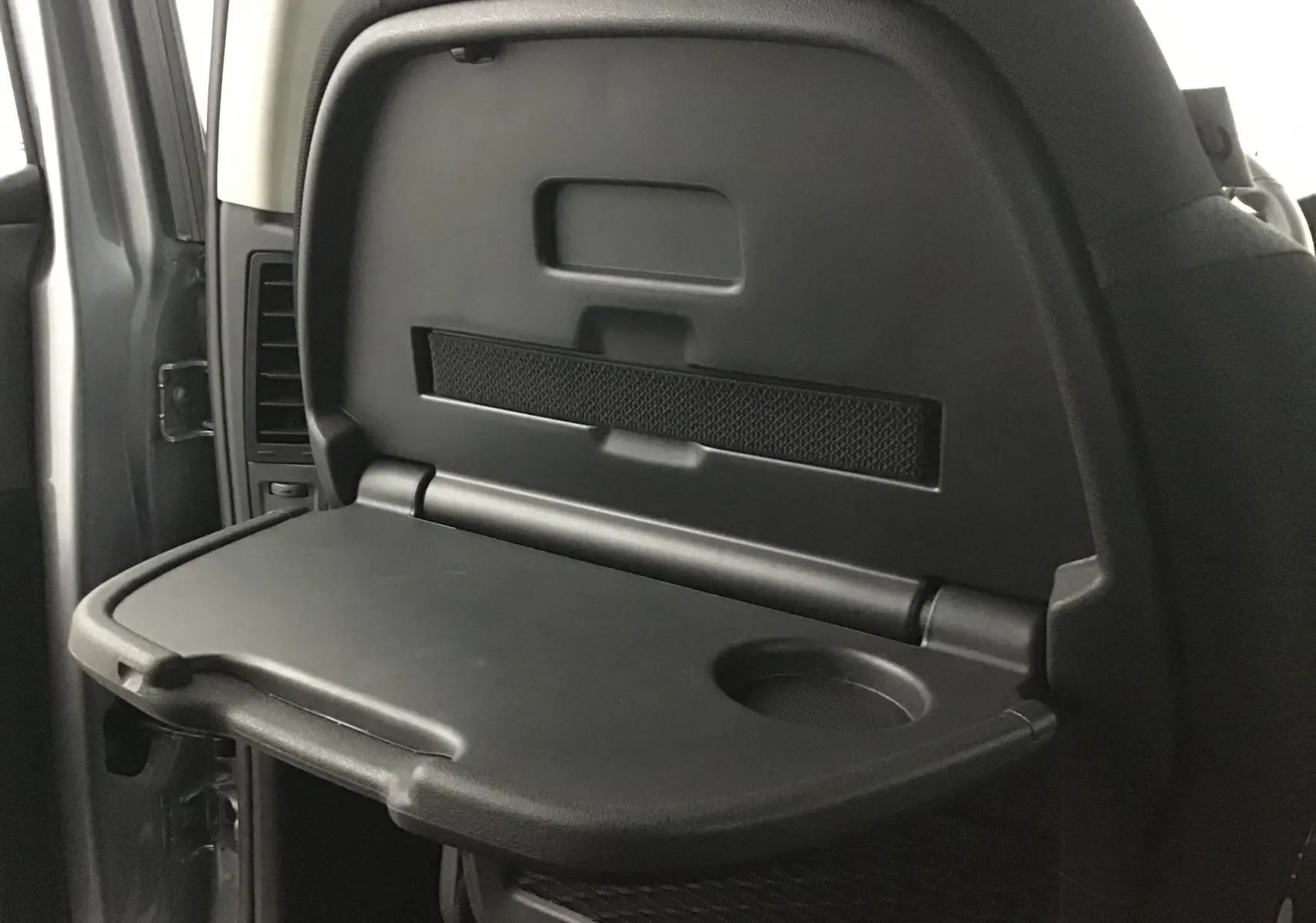 Tablette rabattable noire avec porte-gobelet intégrée sur le dossier d'un siège arrière d'un Citroën Grand C4 Spacetourer gris Artense.