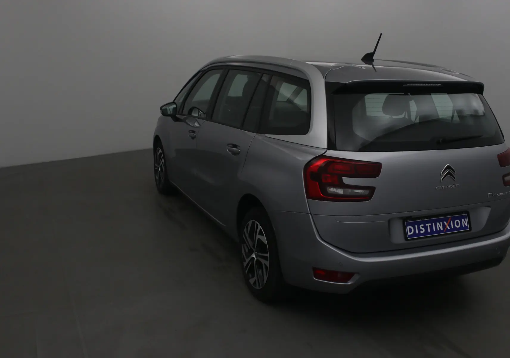 Vue 3/4 arrière gauche d'un Citroën Grand C4 Spacetourer gris Artense avec feux arrière distinctifs et antenne toit.
