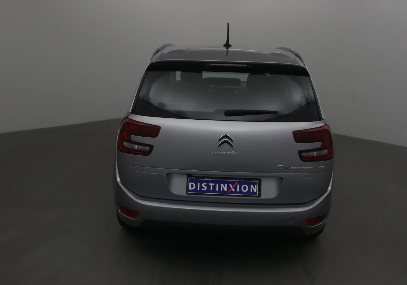 Vue arrière d'un Citroën Grand C4 Spacetourer gris Artense avec feux arrière distinctifs et logo central.
