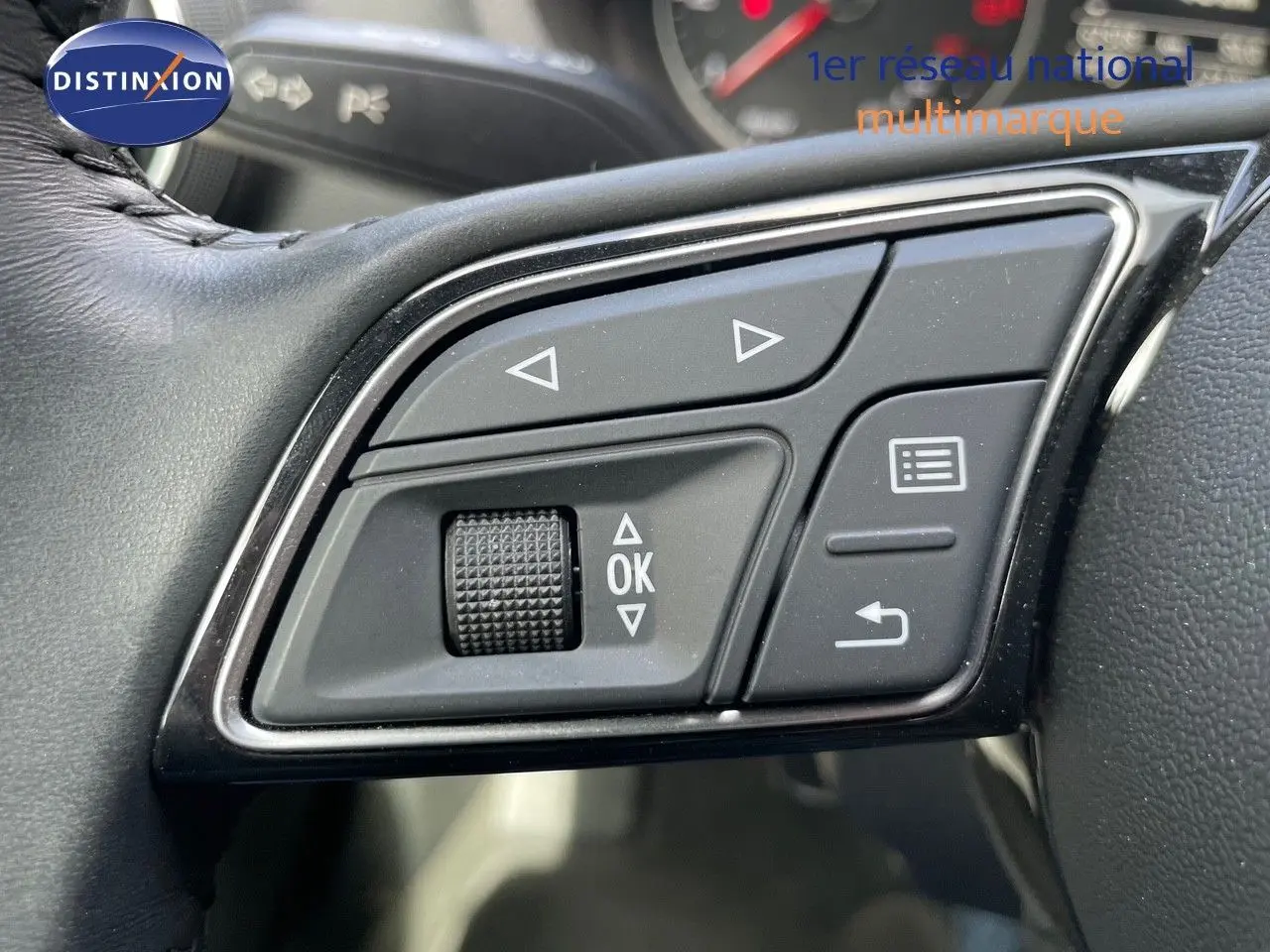 Gros plan sur les commandes au volant de l'Audi A3 Sportback 35 TFSI bleu cosmos, boutons de navigation et validation visibles.
