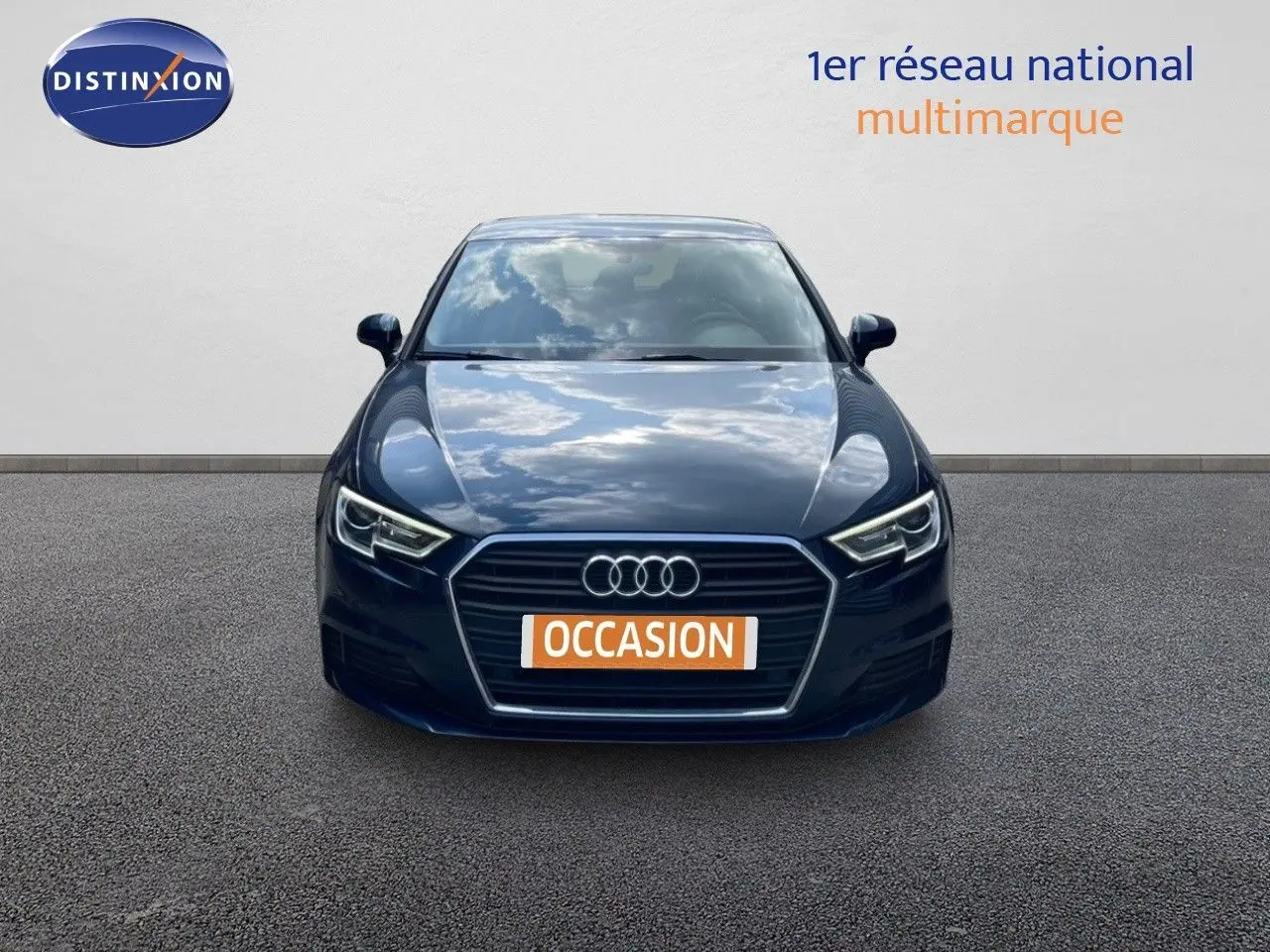 Vue frontale d'une Audi A3 Sportback bleu cosmos métal avec calandre hexagonale et phares LED allumés.
