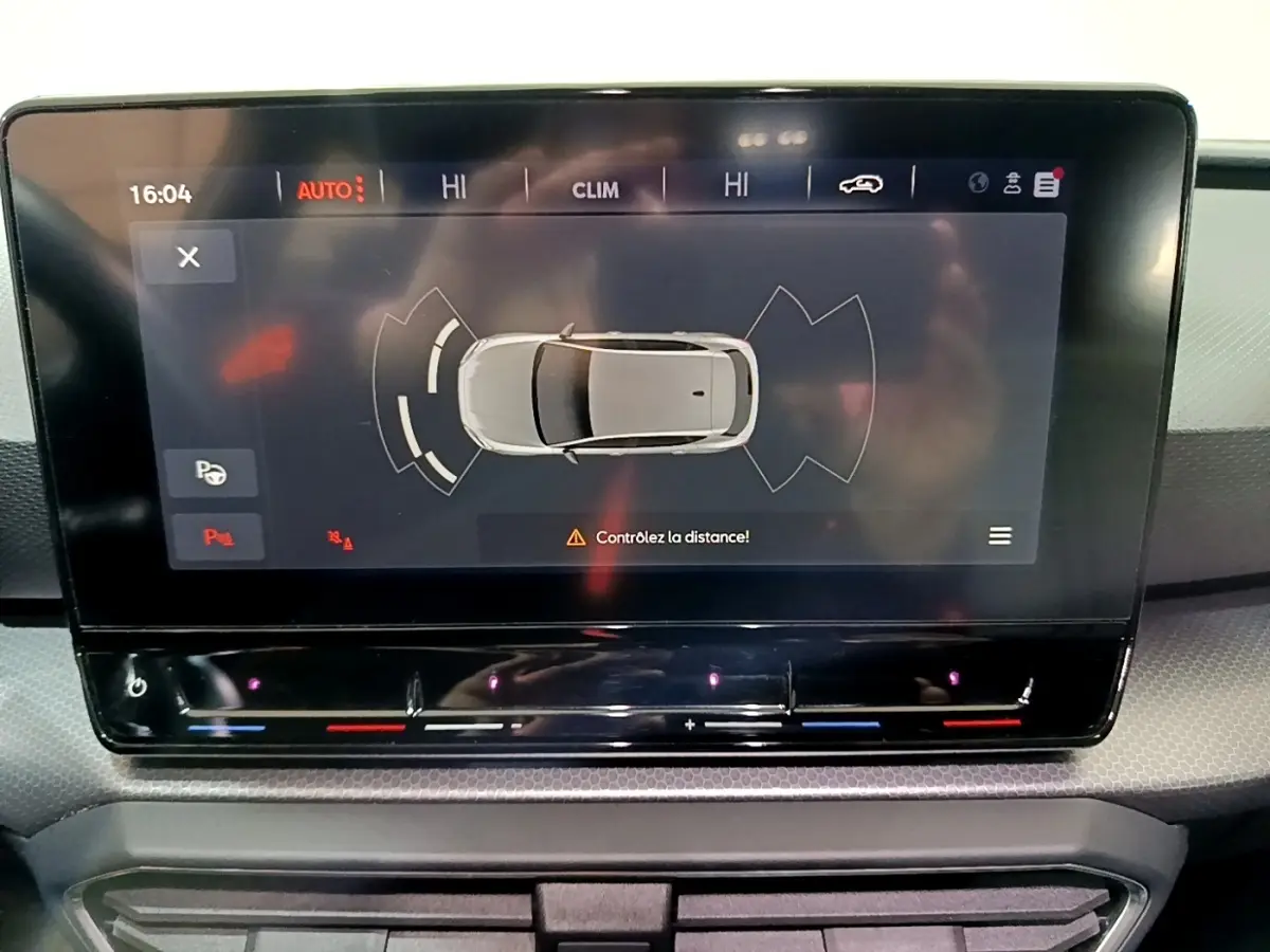 Écran tactile central affichant l'aide au stationnement avec vue aérienne du véhicule gris clair SEAT Leon 2023.