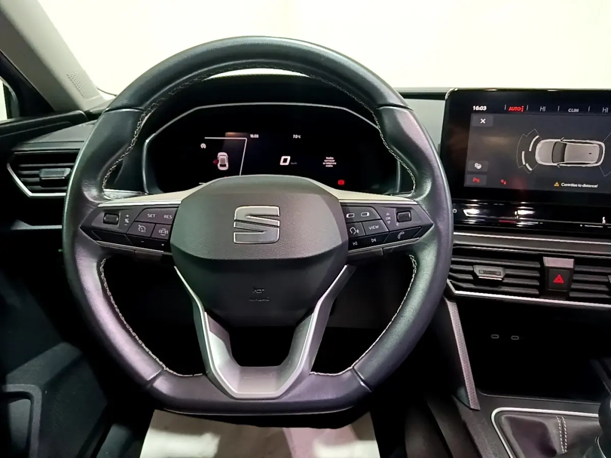 Vue intérieure centrée sur le volant cuir noir du SEAT Leon 2023 avec tableau de bord digital et écran tactile.