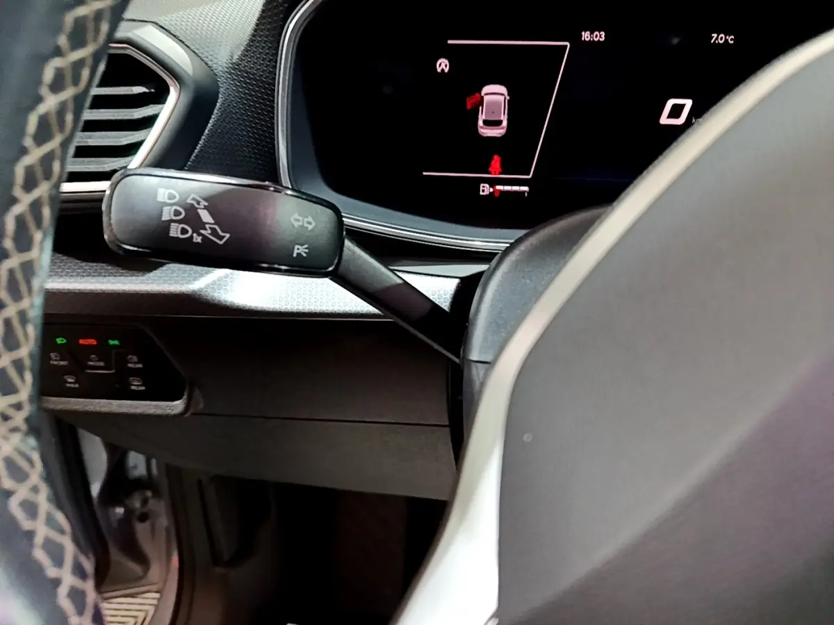 Détail du tableau de bord et levier de clignotants dans l'habitacle gris clair d'une SEAT Leon 2023.