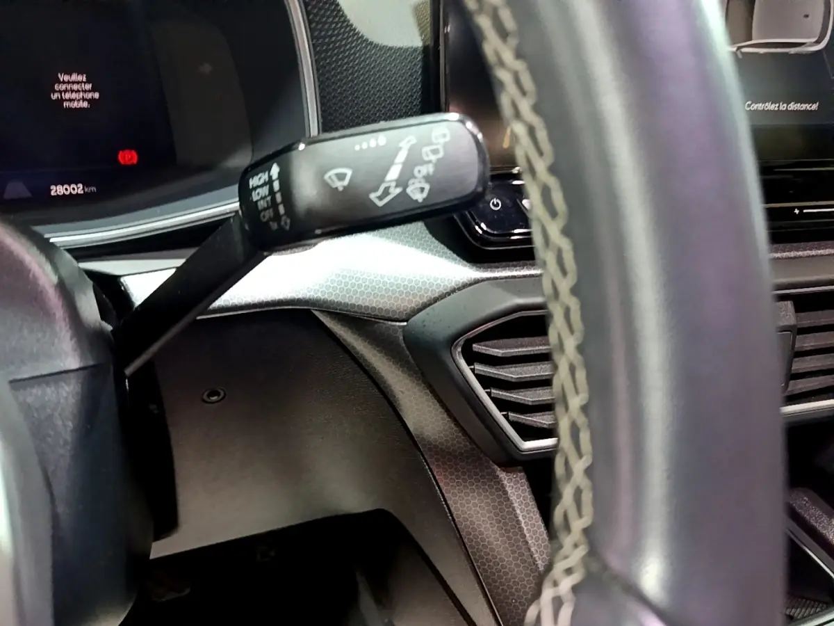 Gros plan sur la manette d’essuie-glace à gauche du volant en cuir avec surpiqûres dans l’habitacle gris du SEAT Leon.